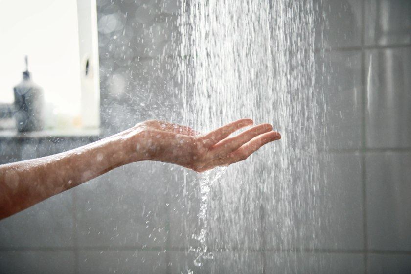 Hand onder een waterstraal van de douche