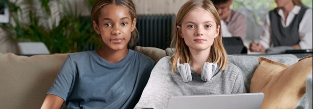 Twee stoere jonge meisjes op de bank met een laptop - tarieven stadsverwarming
