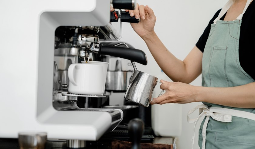 Vrouw staat koffie te maken in een cafeetje denkt na over energiesubsidies 2024