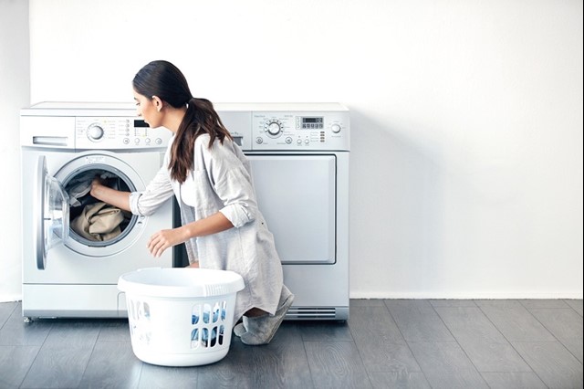Vrouw zit gehurkt bij wasmachine om energiezuinig te drogen