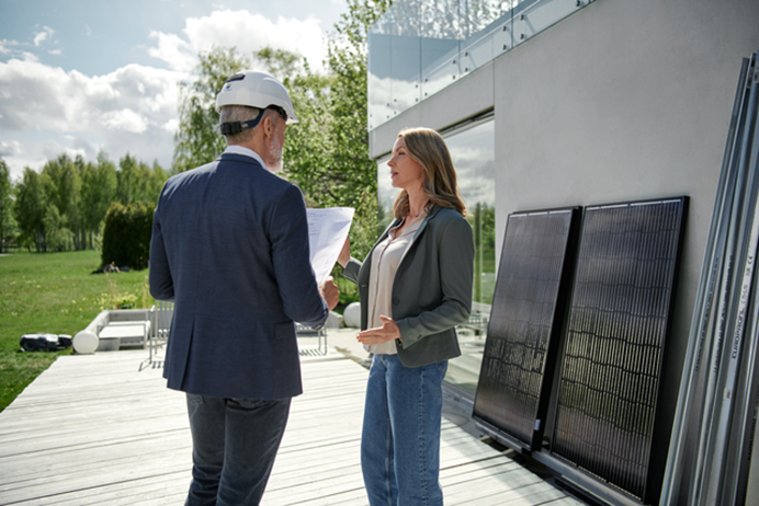 Man en vrouw staan buiten te overleggen bij zonnepanelen