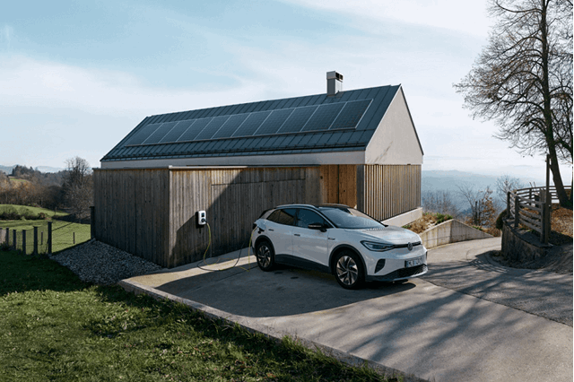 Elektrische auto aan een laadpaal bij een huis met zonnepanelen