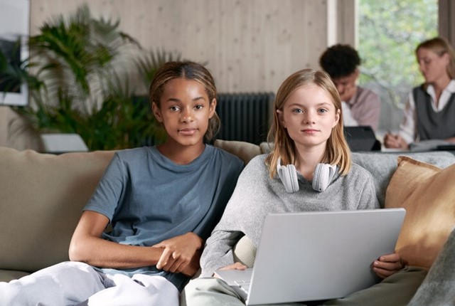 Twee slimme meiden zitten op de bank en werken op de laptop | Vattenfall energie
