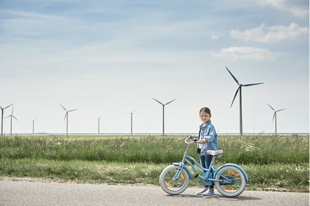 Iemand staat met een fiets op een nieuwe weg in een veld met windmolens