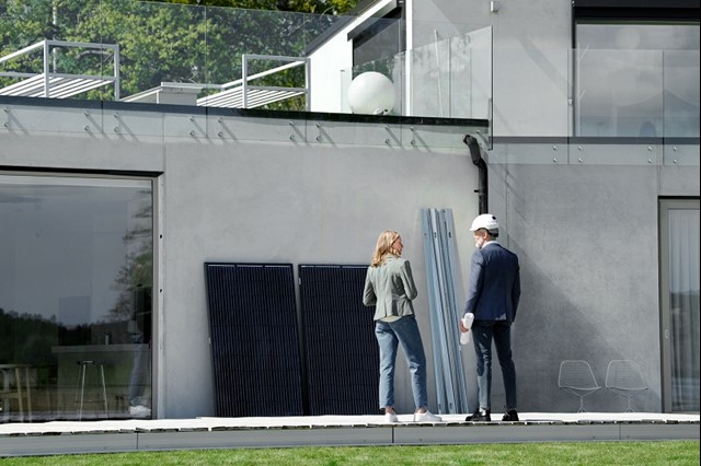 Vrouw praat met technische man over de zonnepanelen voor op dak