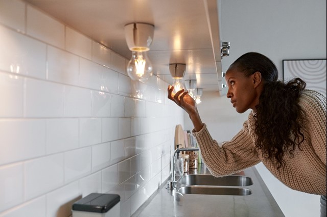 Vrouw draait een nieuwe ledlamp in om het aanrechtblad te verlichten | Vattenfall over goedkope energie