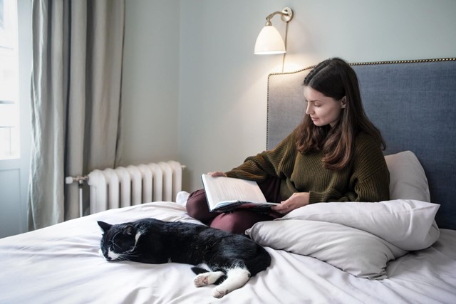 Vrouw met kat leest een boek op bed, Vattenfall cv-ketel informatie