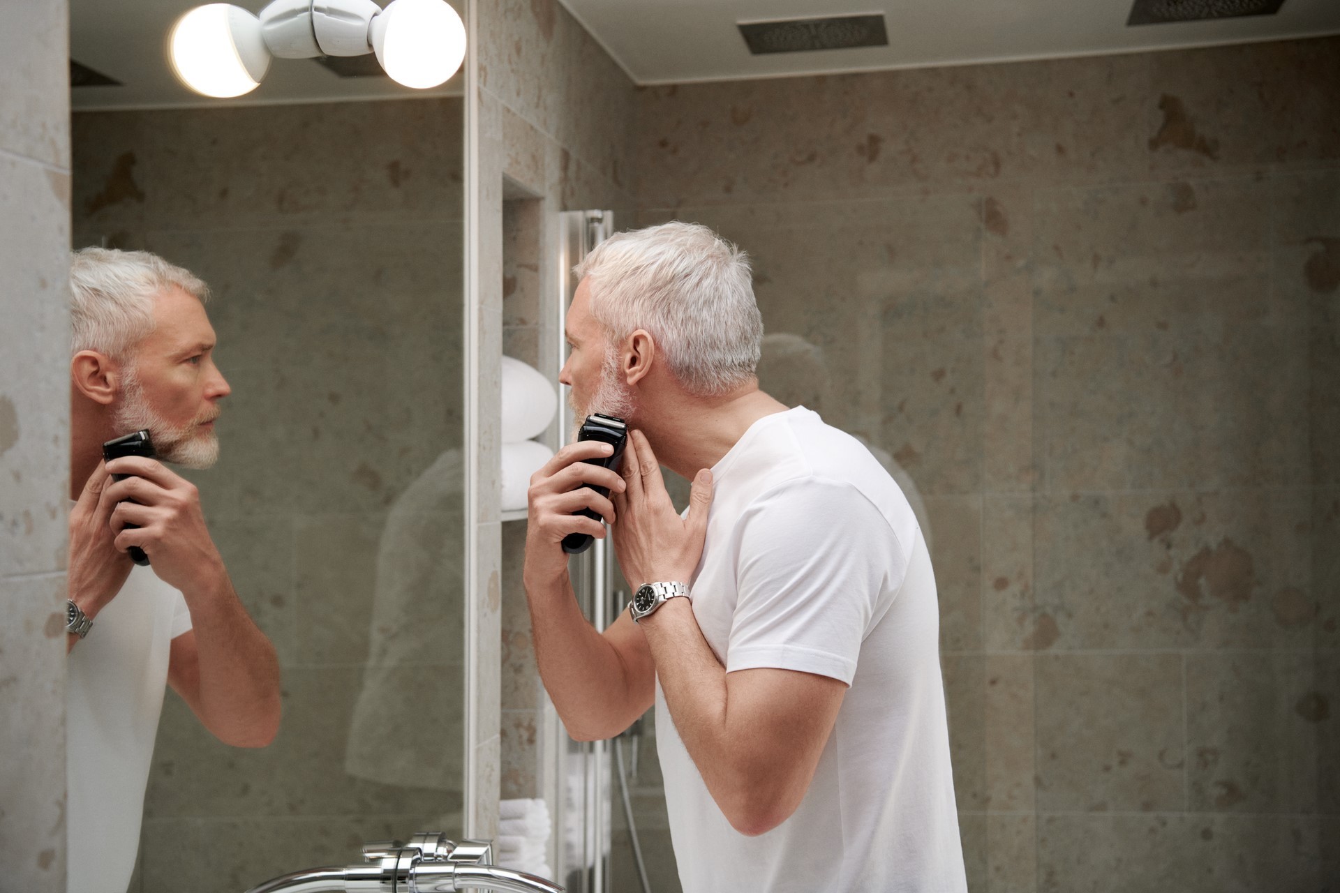 Man scheert zich voor de spiegel in de badkamer