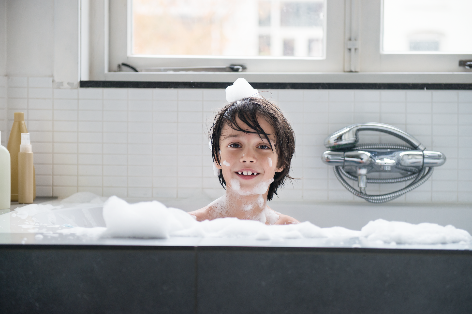 Jongen zit in een bad met veel schuim