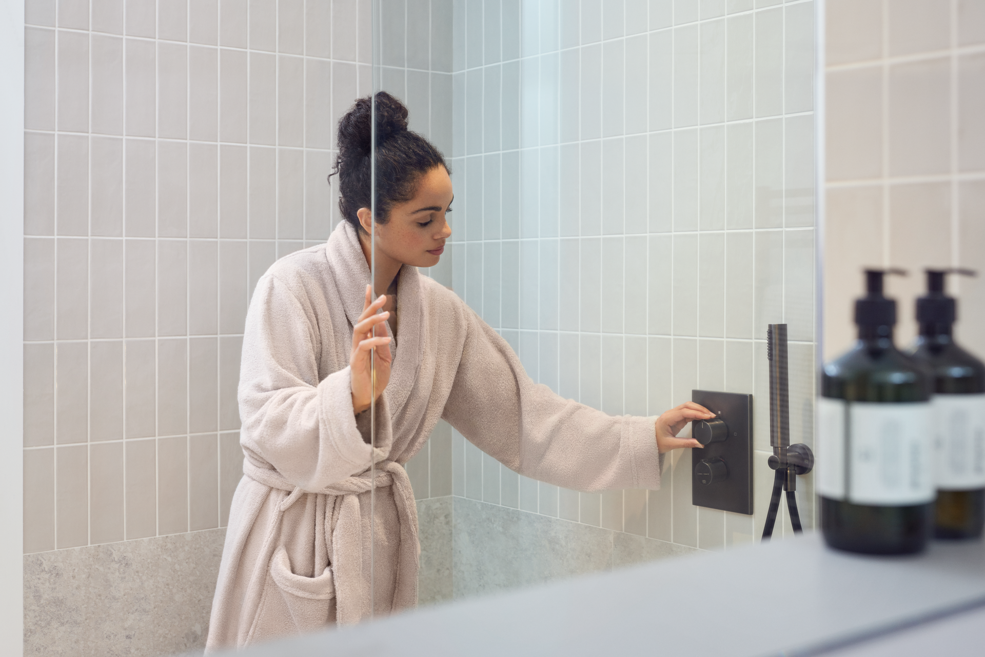 Vrouw in badjas zet de douche aan