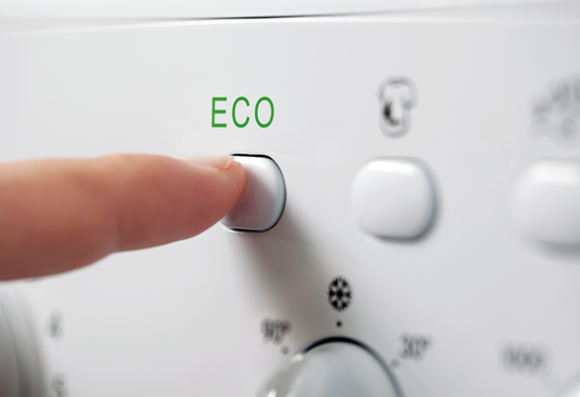 Vinger drukt op de eco-knop van de wasmachine