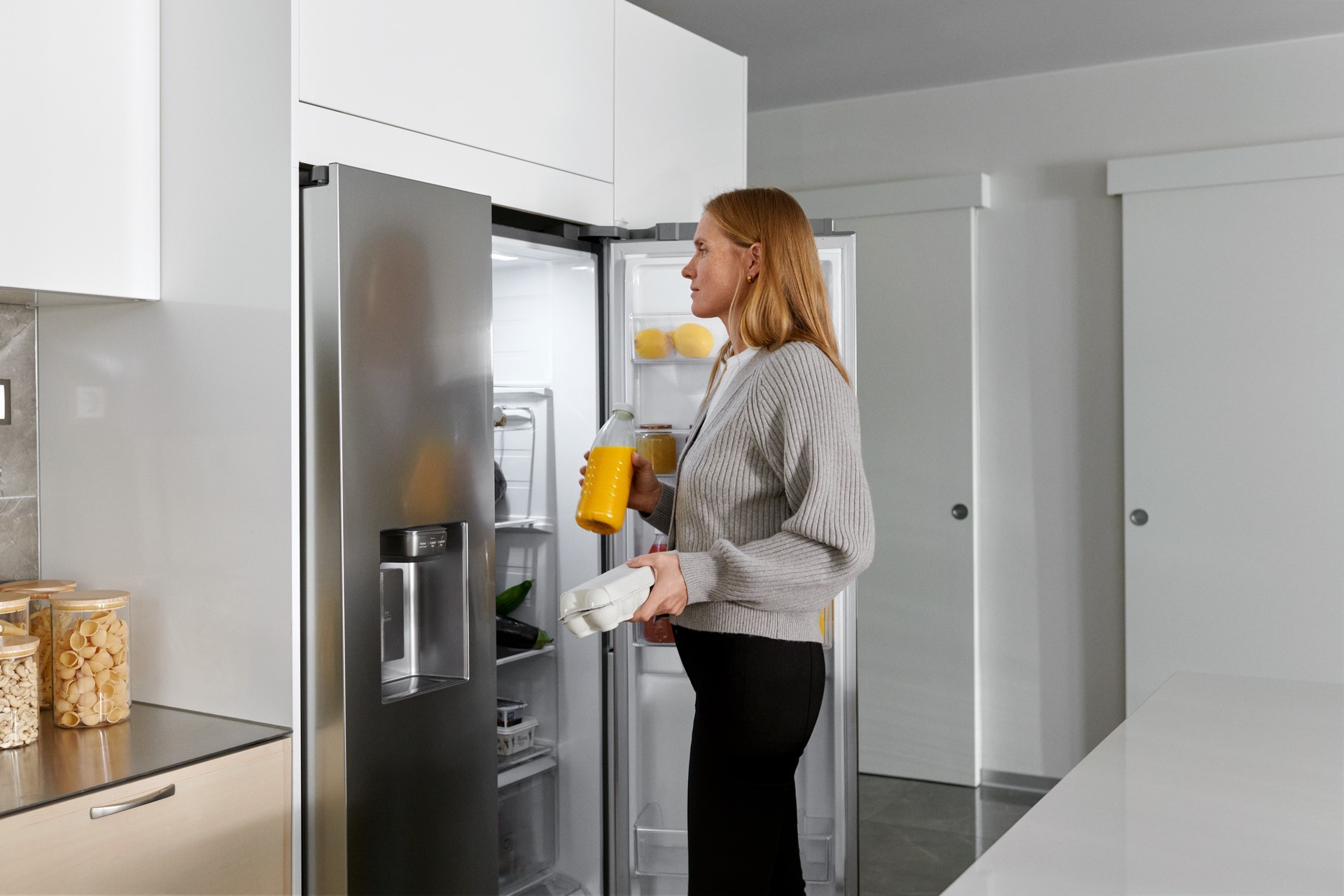Vrouw pakt eieren en sinaasappelsap uit de koelkast