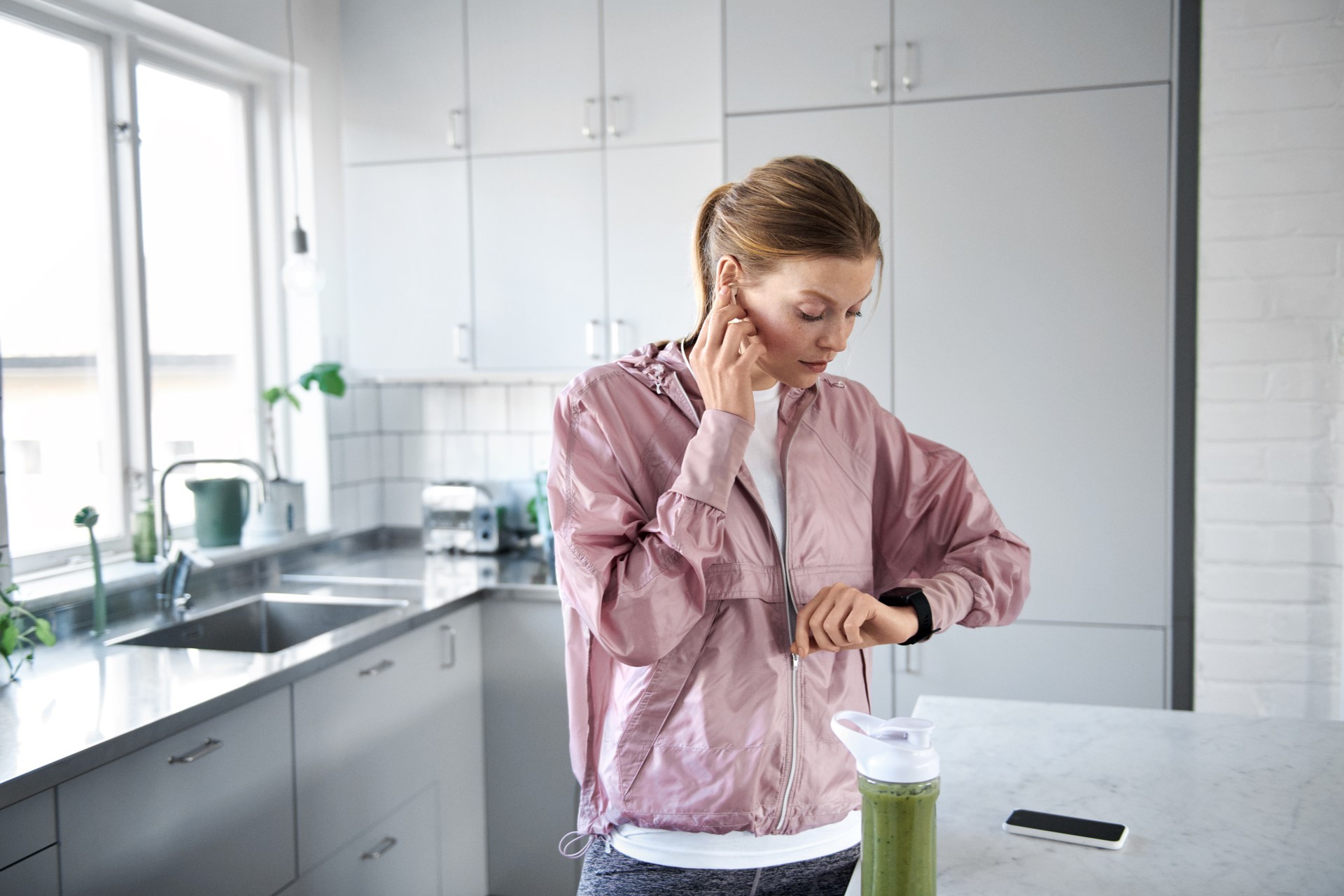 Vrouw staat in de keuken en kijkt op haar smartwatch