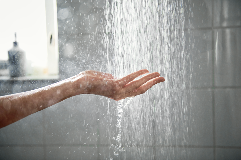 Een hand in een straal met water van de douche