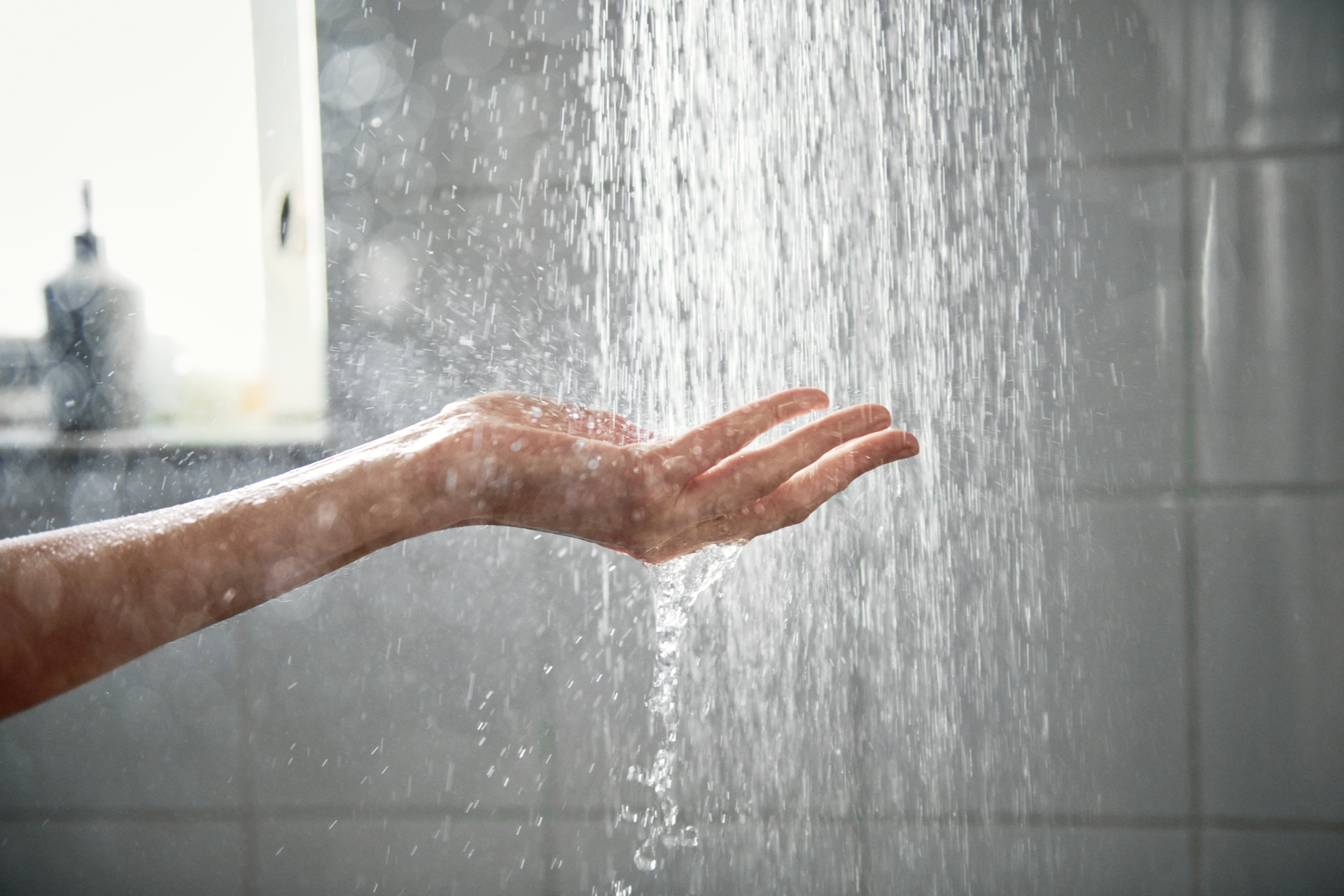 Hand onder de douche met een waterstraal