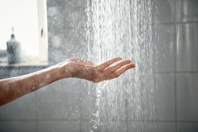 Iemand houdt haar hand onder het douchewater