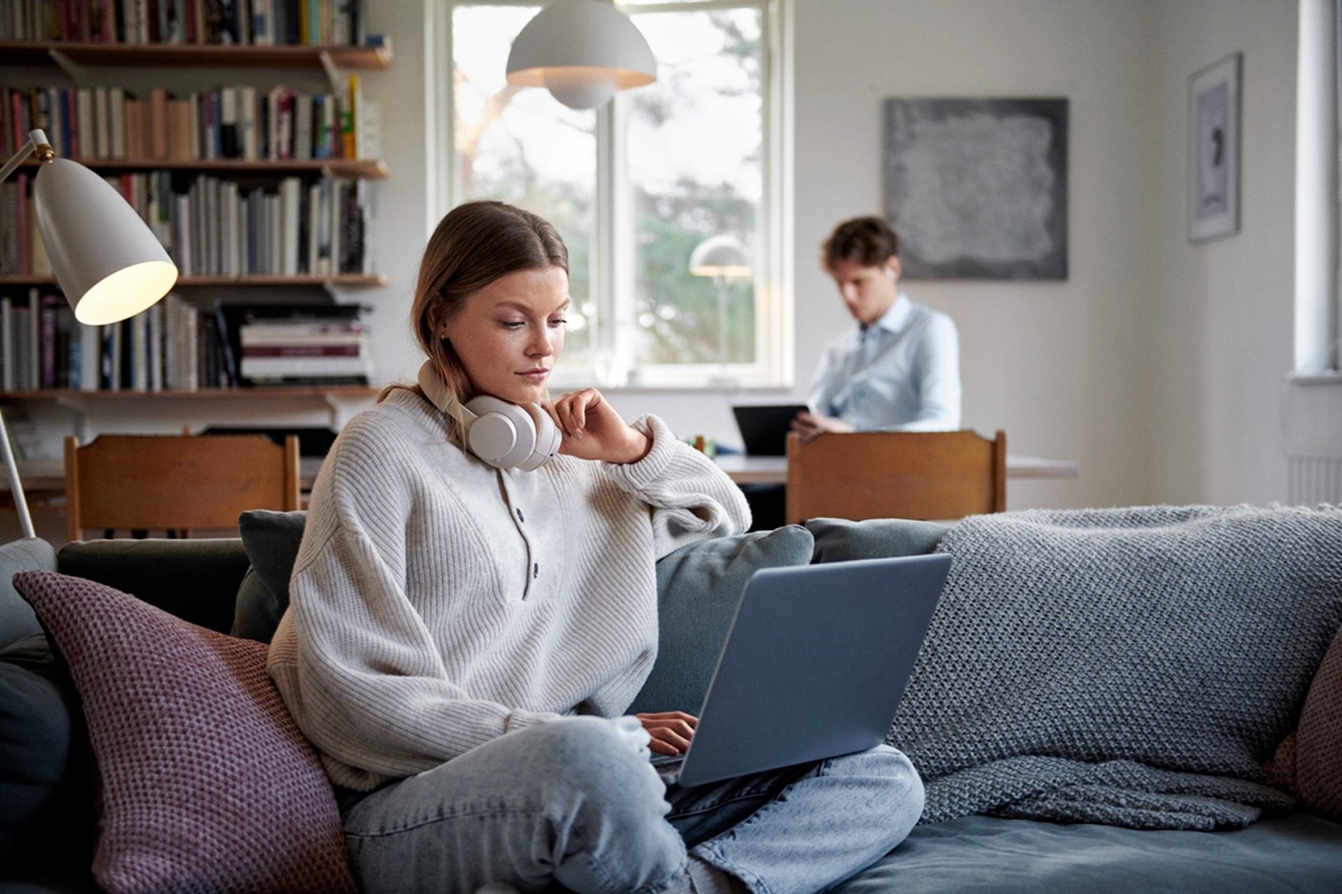 Vrouw zit met laptop op de bank en leest informatie van Vattenfall over gevelisolatie