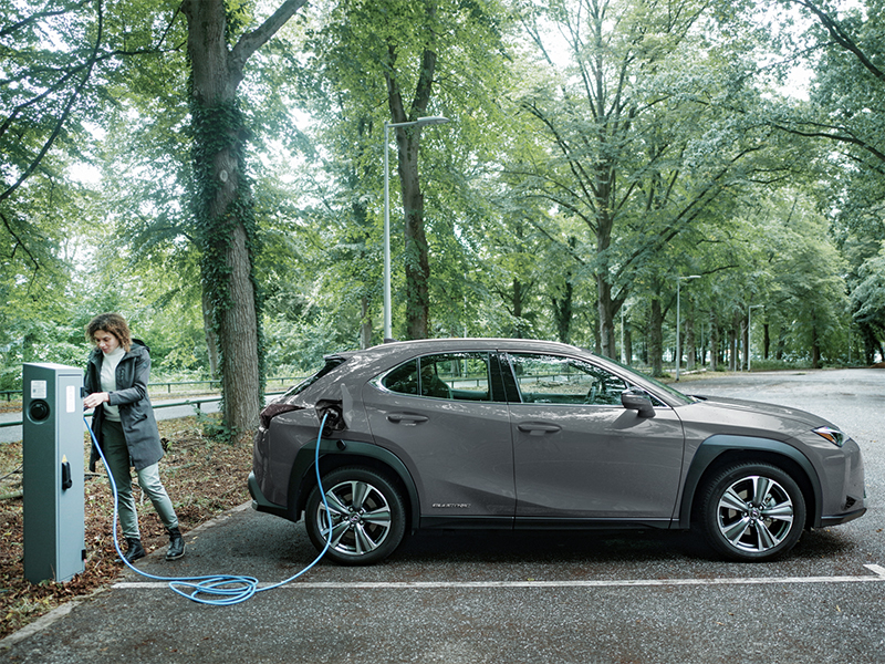 Elektrisch opladen auto | Vrouw laadt op een parkeerplaats haar auto op