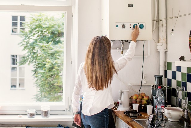 Vrouw checkt de boiler in haar keuken - Bespaaradvies