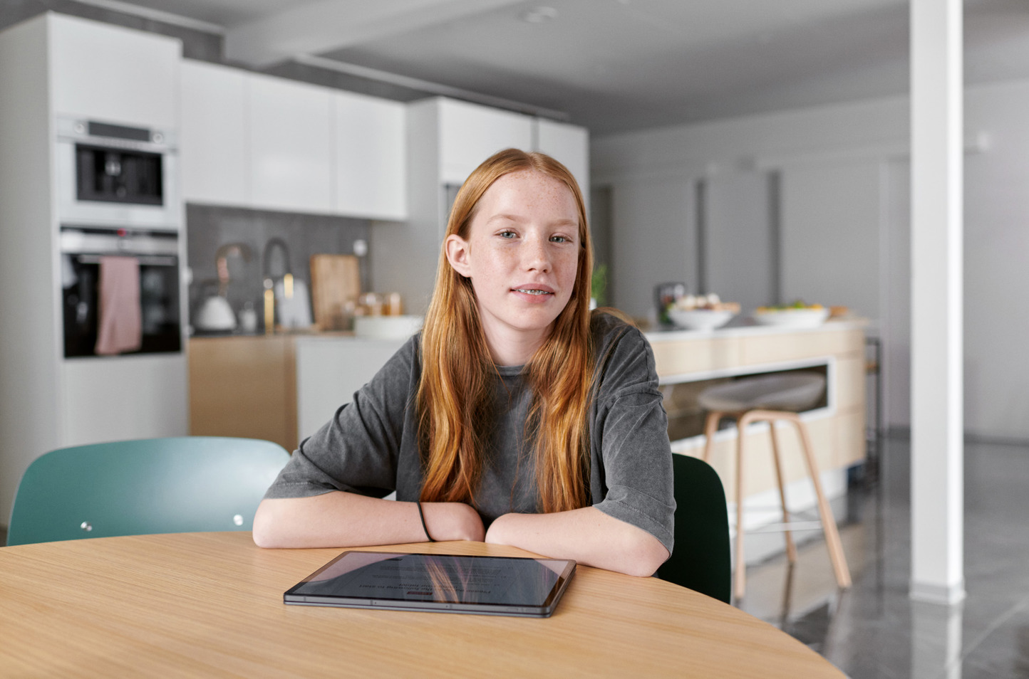 Meisje aan keukentafel met tablet