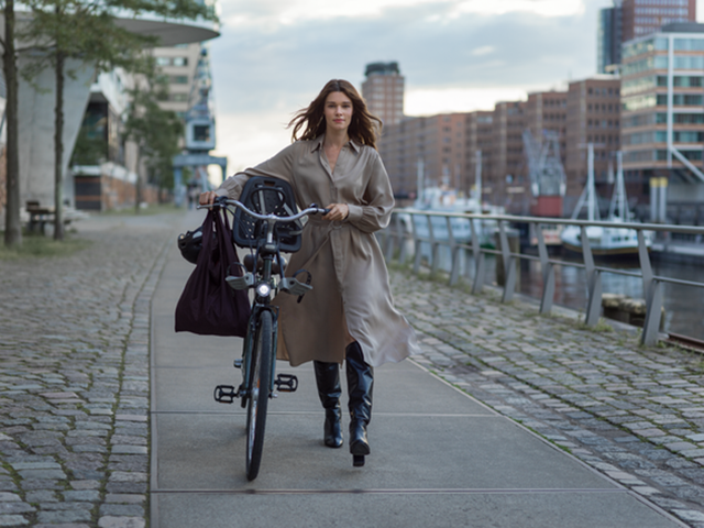 Vrouw loopt met fiets langs kade