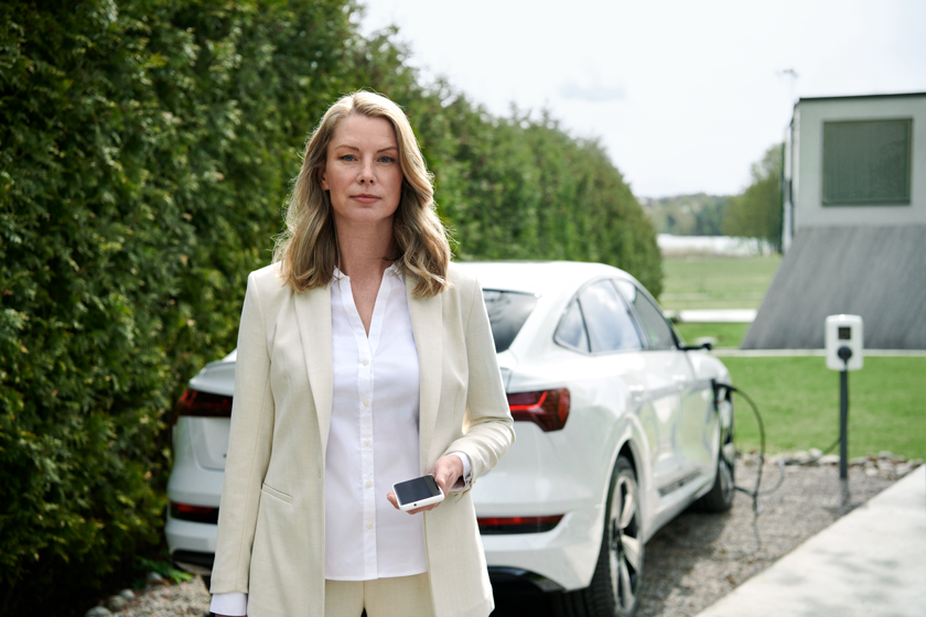 Zakelijk geklede vrouw staat bij haar auto