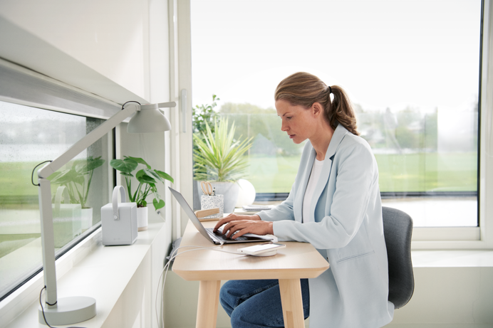 Mevrouw achter bureau bekijkt op laptop tips om te energie te besparen