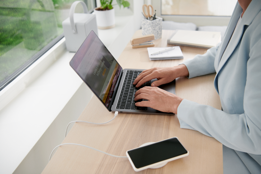 Vrouw bij raam met laptop en smartphone