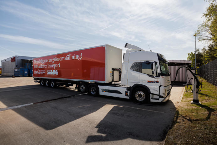 Een vrachtwagen van Coca Cola naast een laadstation