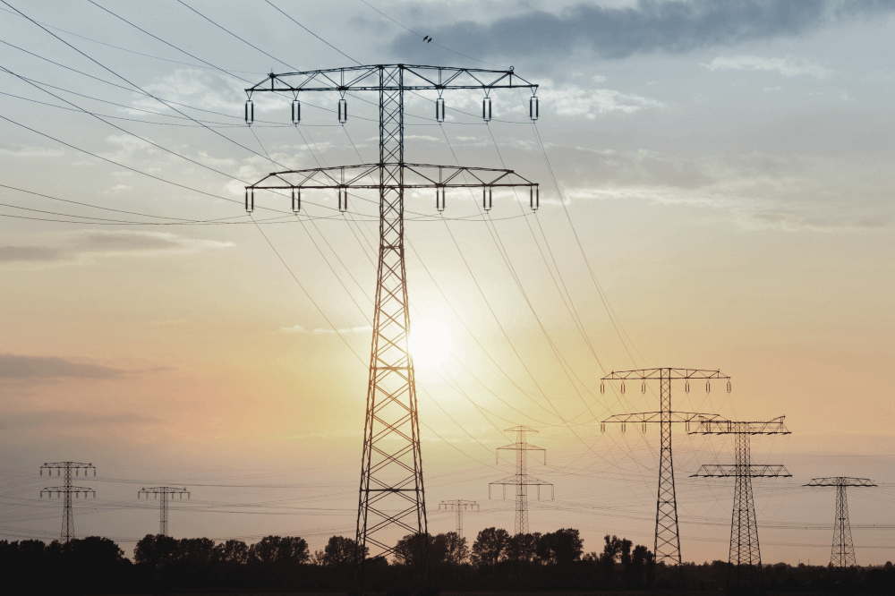 Rij van elektriciteitsmasten tegen een ondergaande zon