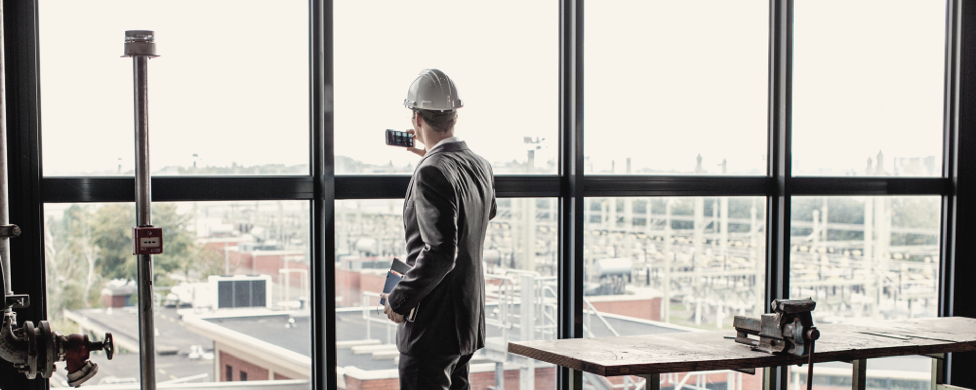 Man met fotocamera die naar buiten kijkt over terrein