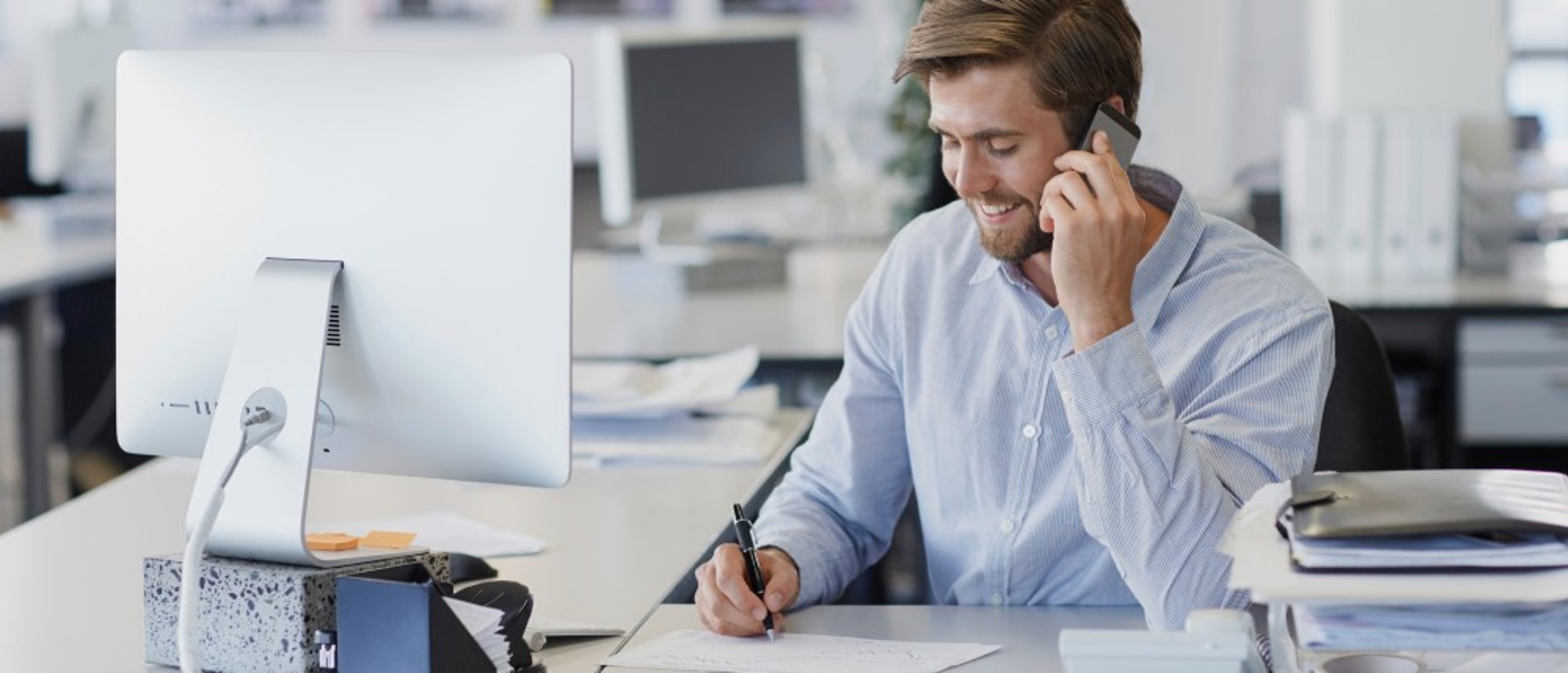 Man aan de telefoon met een beeldscherm op de voorgrond