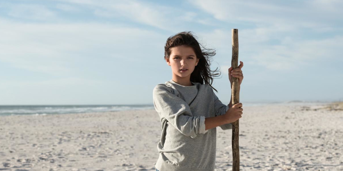Meisje met stok op het strand