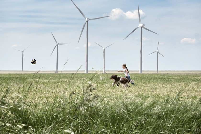 Meisje rent met haar hond in een windmolenpark