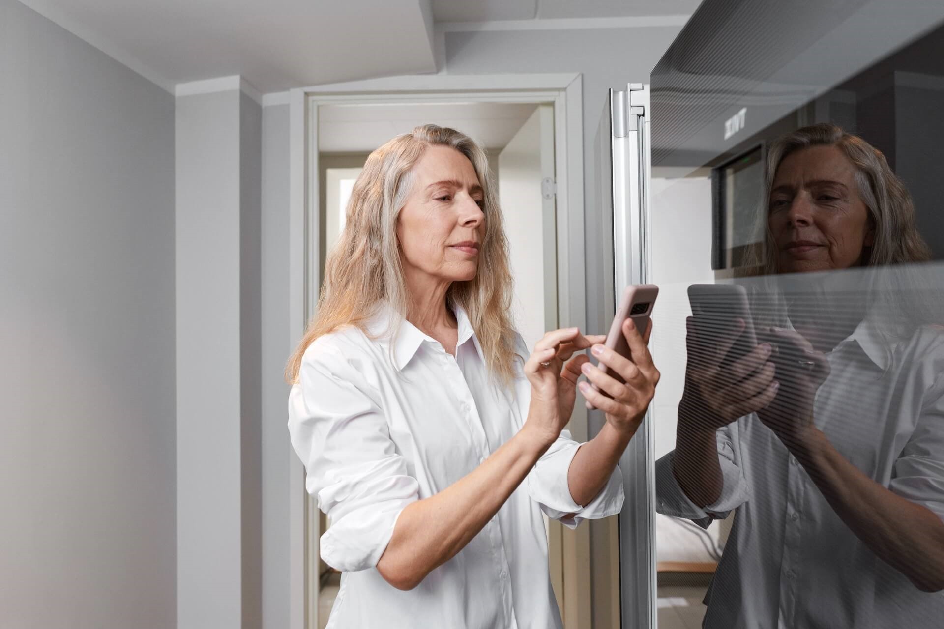 Vrouw checkt de verwarming in haar huis met behulp van haar smartphone. In verband met energiebelasting en overheidsheffingen