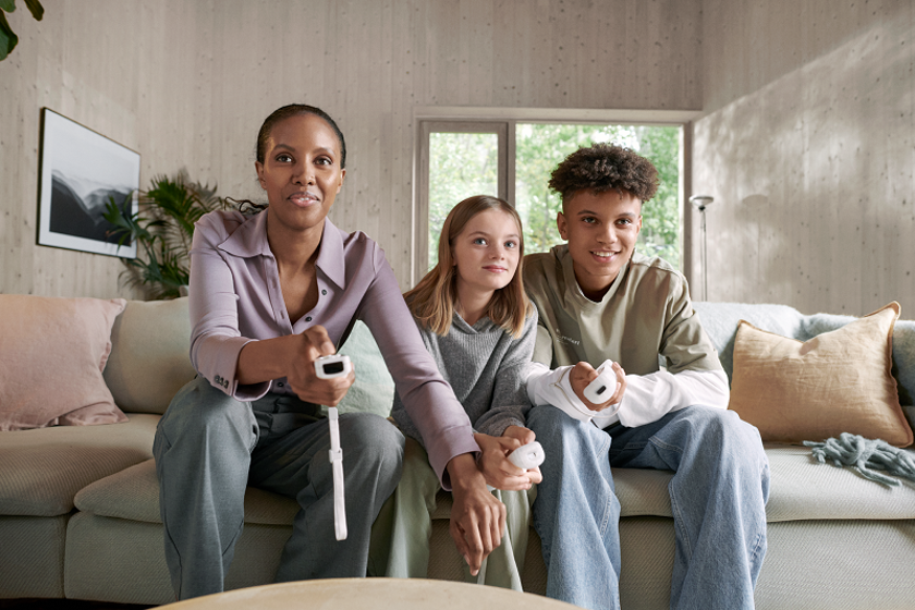 Vriendelijk lachende moeder met zoon en dochter op de bank spelen videospel