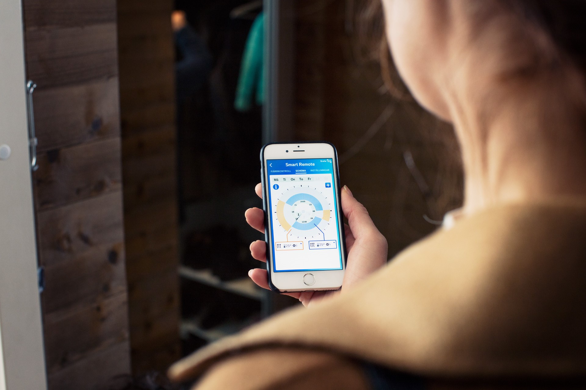 Close-up van een mobieltje in de hand van iemand die het licht regelt via een app | Vattenfall over wat is een smart home