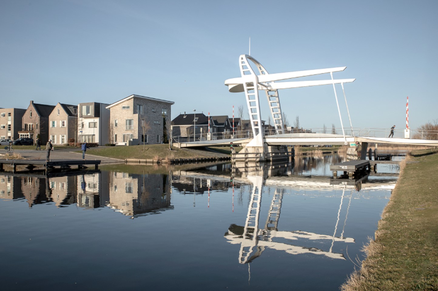 Een witte brug en woningen in Almere Noorderplassen West
