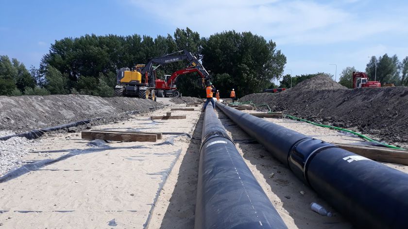 Warmtetransportleidingen in Amsterdam Zuidoost en een graafmachine met Vattenfall medewerkers