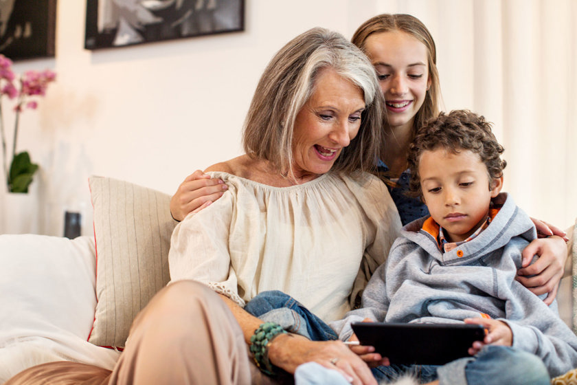 Vrouw en kinderen samen op de bank, kijken op tablet l Vattenfall energie