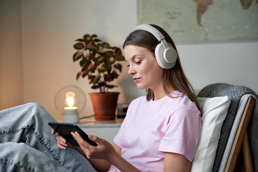 Vrouw met koptelefoon op leest op haar tablet