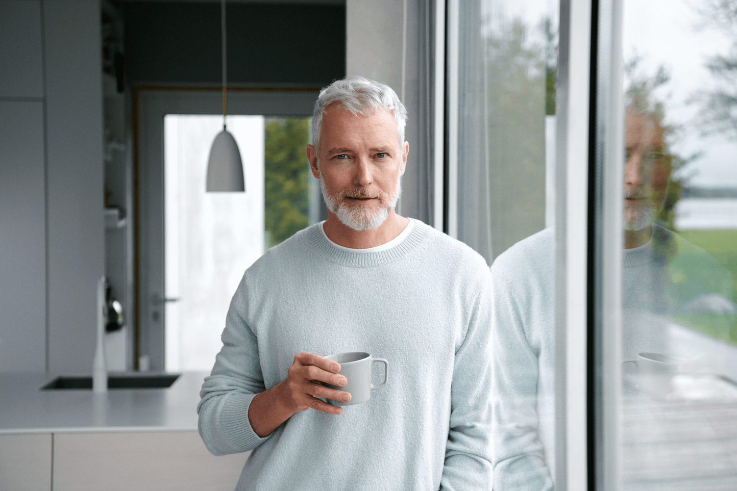 Man met kop koffie bij glazen deur