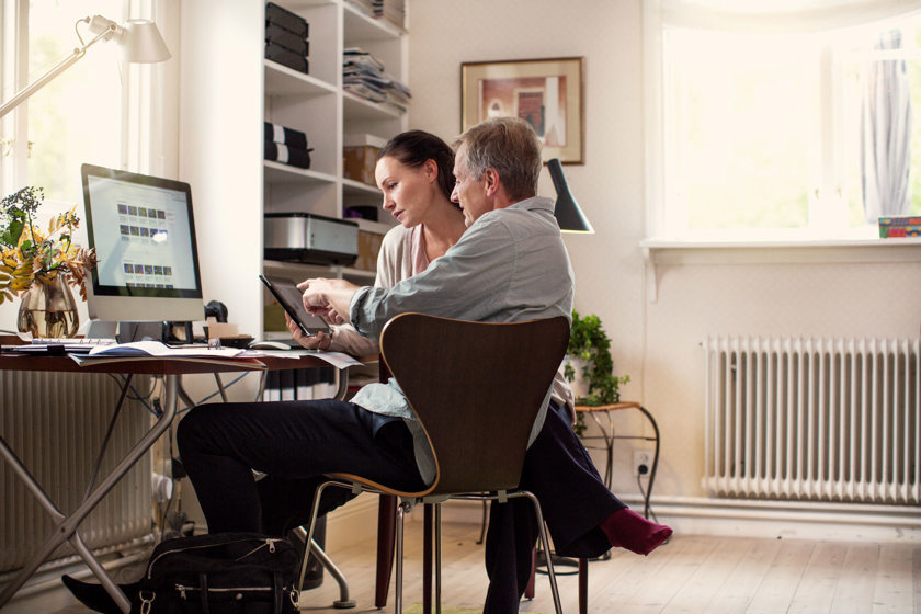 Schuldhulp | Echtpaar thuis achter een bureau kijkend op hun laptop 