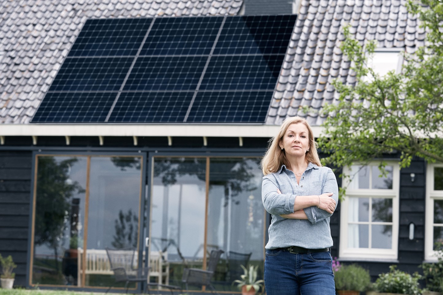 Vrouw voor huis met zonnepanelen | Vattenfall energie