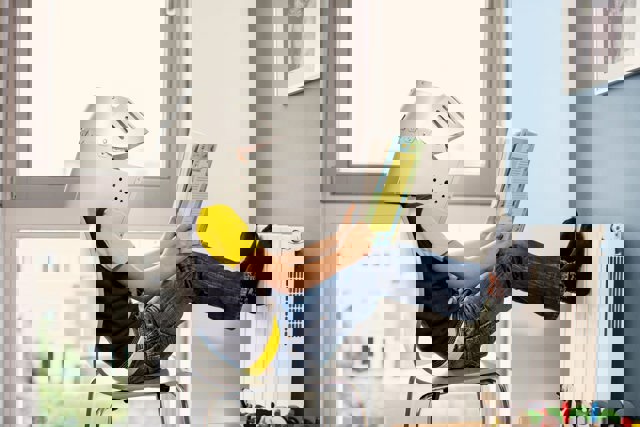 Jongetje met masker leest een boek bij verwarming | Vattenfall
