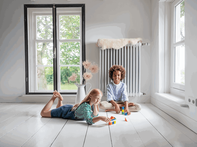 Kinderen spelen op de vloer in de woonkamer - Op weg naar fossielvrije stadswarmte