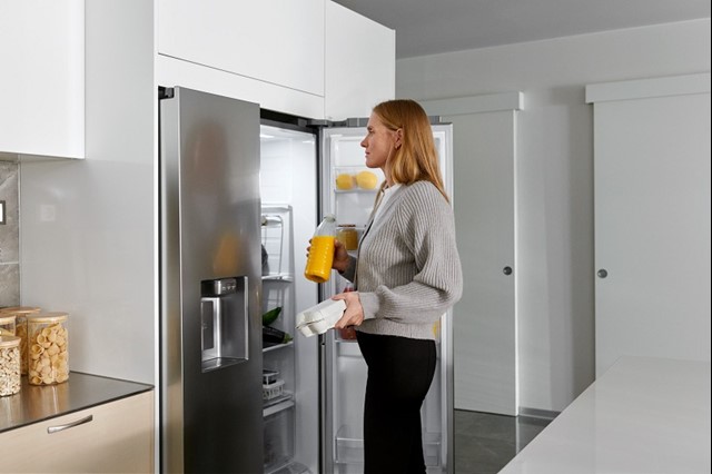 Vrouw pakt eieren en sinaasappelsap uit de koelkast