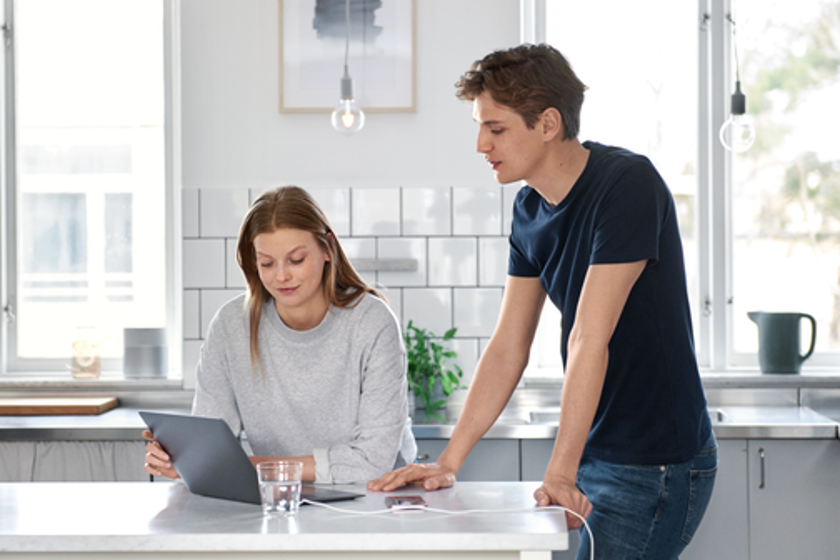 Jonge vrouw en man met laptop in de keuken