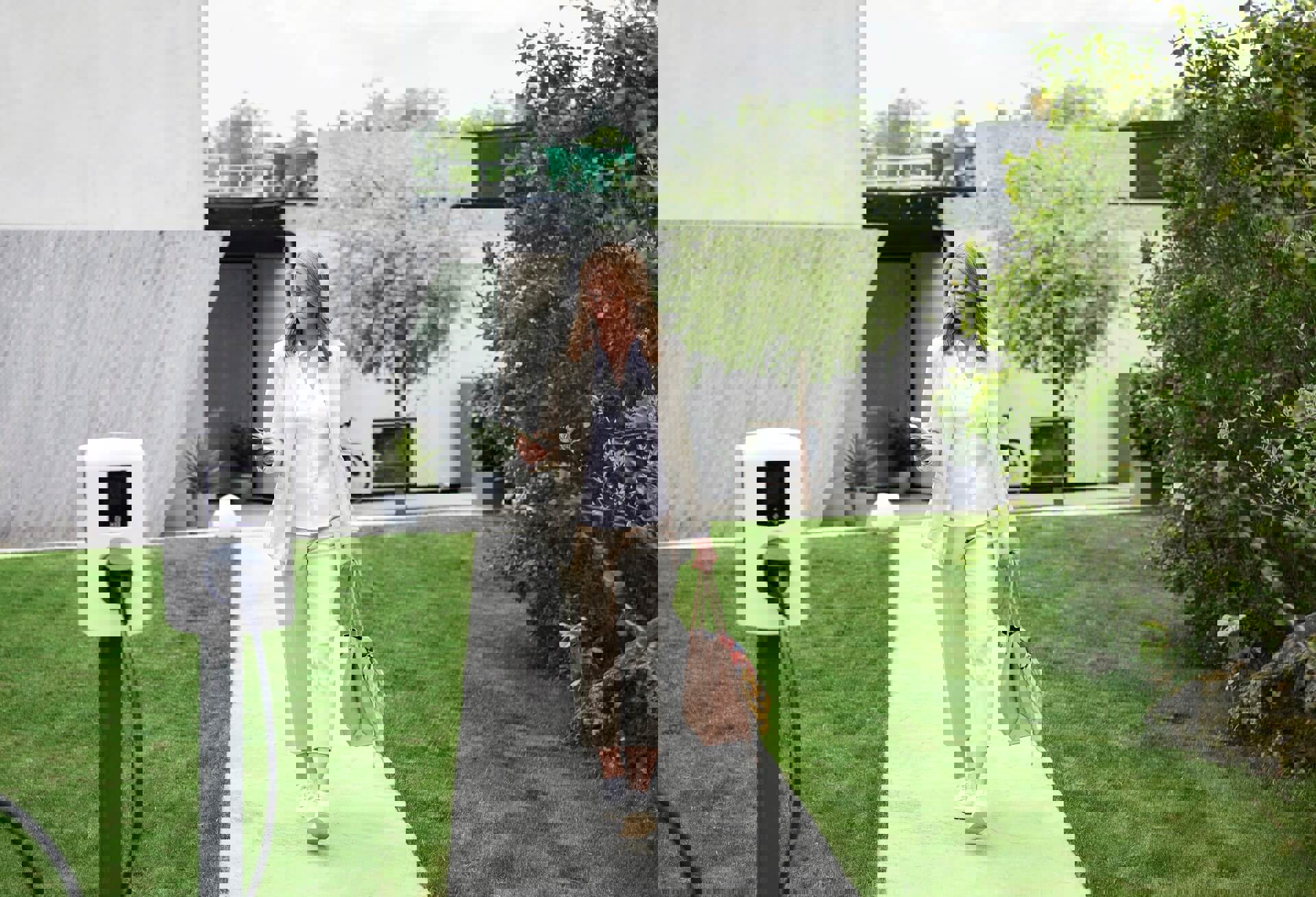 Vrouw loopt langs laadpaal voor haar huis | Welke laadpaal kies ik voor thuis?