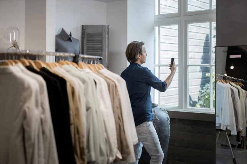 Een ondernemer met een eigen winkel videobelt tussen de kledingrekken